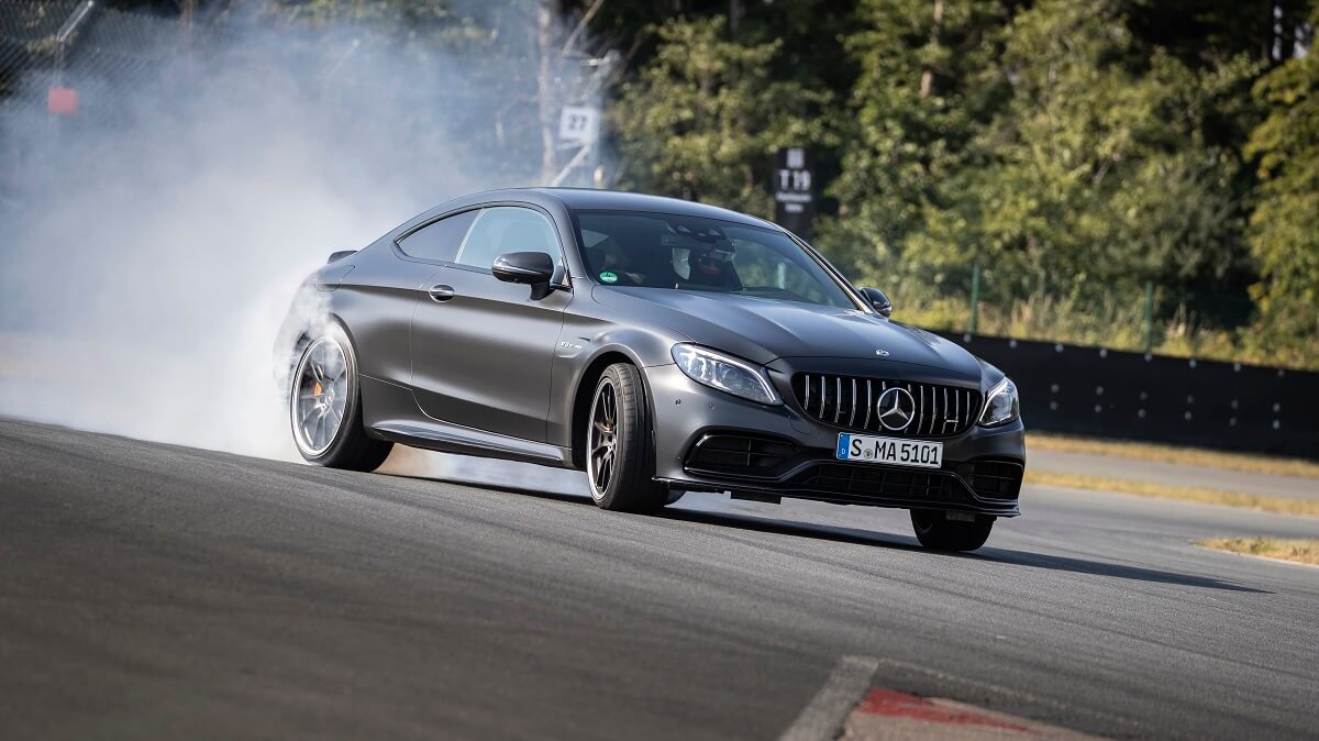 A gray Mercedes-AMG C63 slides in a cloud of smoke.