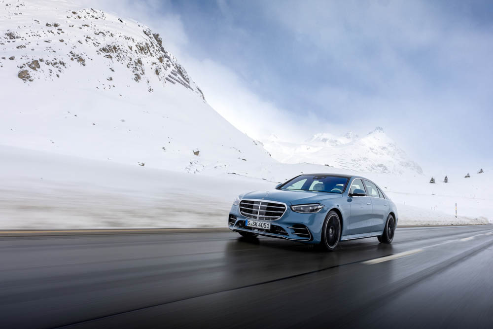 Blue Mercedes Benz S Class Driving down Road beside snow